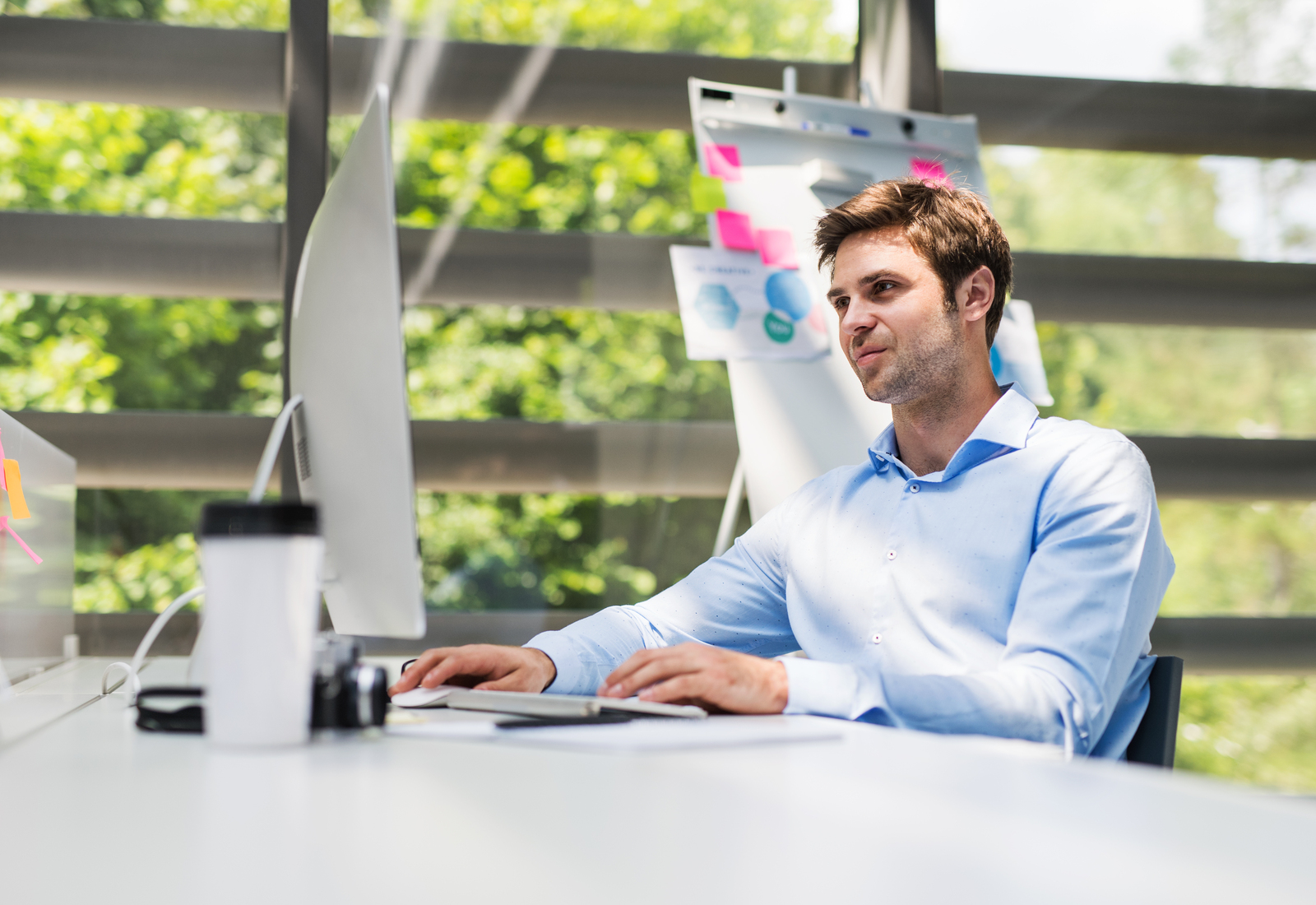 A young businessman in the office sitting at the desk, working.