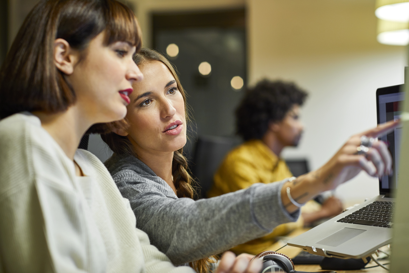 Coworkers discussing over computer in office