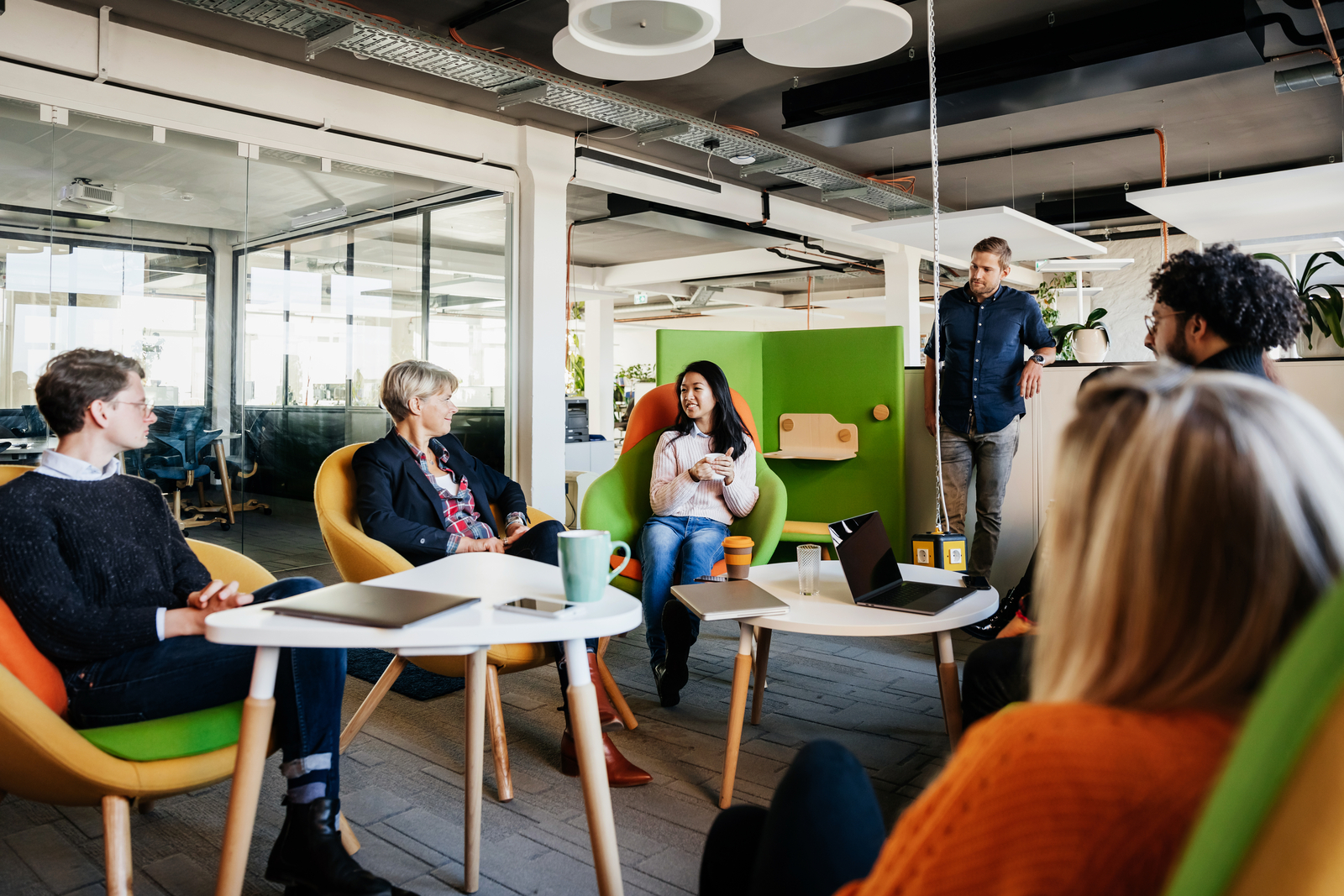 A meeting between the team leaders siting in a circle and brainstorming in a bright and modern office environment.