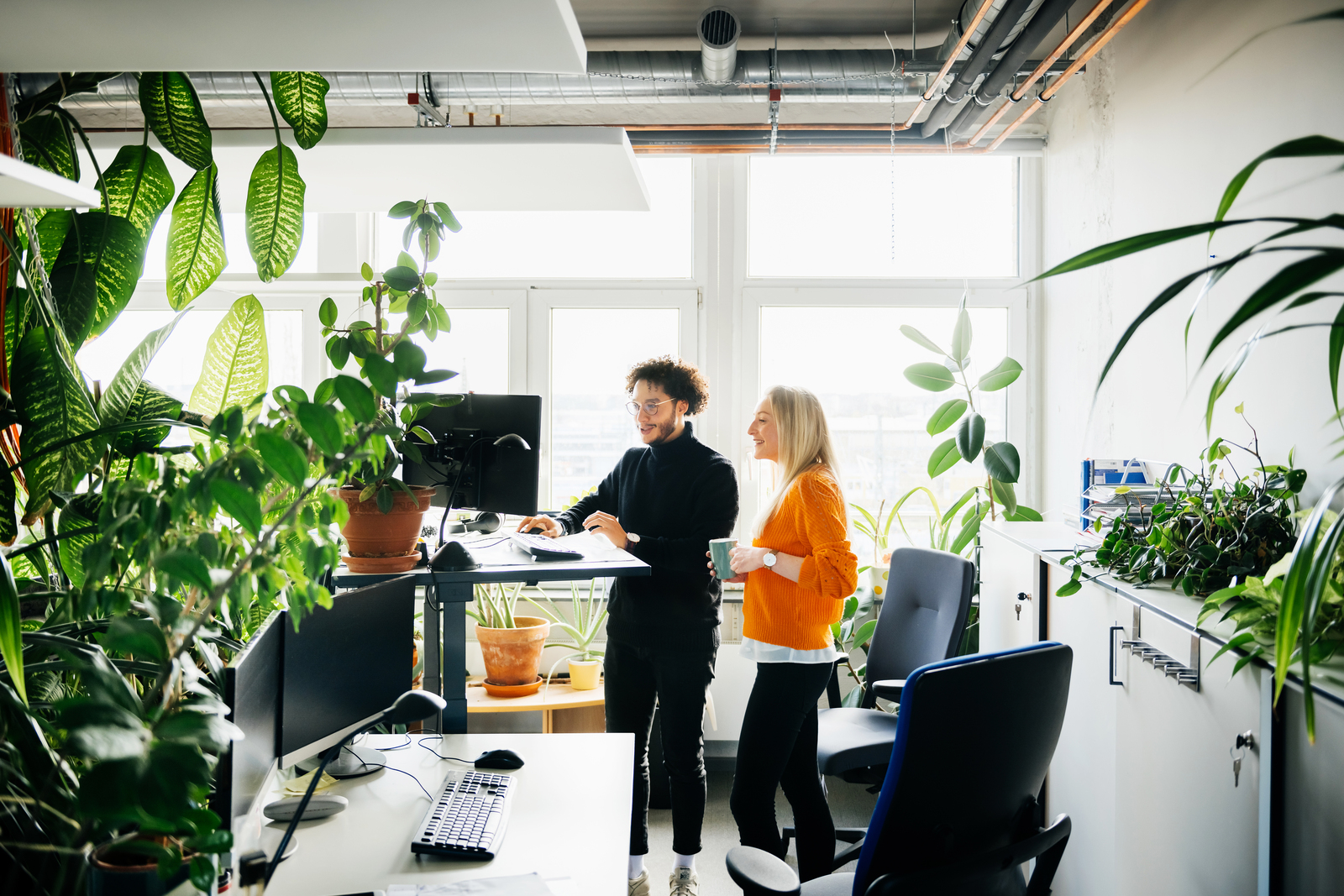 Two office colleagues looking at some work on a computer at a standing desk in a modern office space.